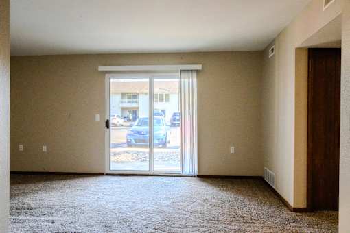 A room with a carpeted floor and a sliding glass door.