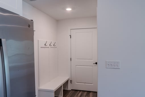A white door is closed in a room with a fridge on the left.
