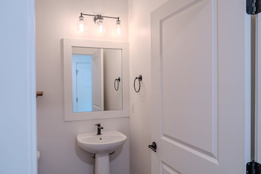 A white bathroom with a sink and mirror.
