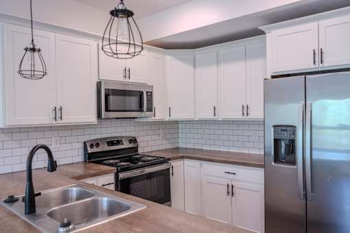 A kitchen with white cabinets and a stainless steel refrigerator.