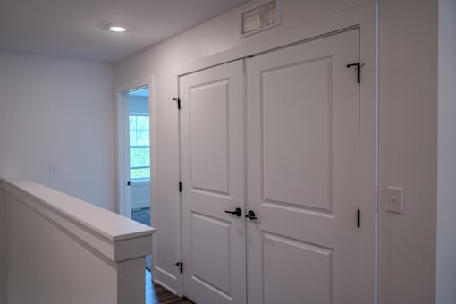 A white door with a black handle is in a room with white walls.