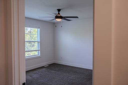 A room with a ceiling fan and a window.