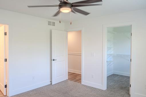 A room with a ceiling fan and carpeted floor.