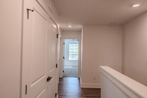 A long hallway with white walls and wood floors.