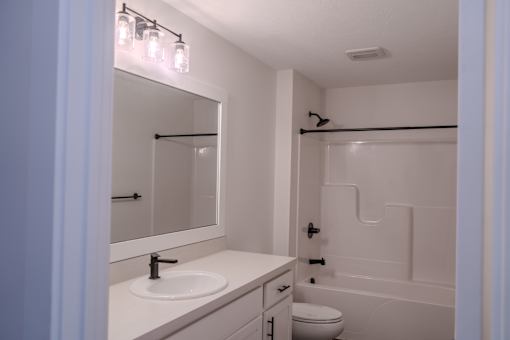 A bathroom with a sink, toilet, and a mirror.