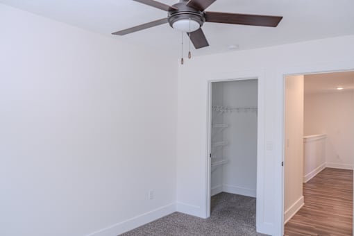 A room with a ceiling fan and a doorway leading to another room.