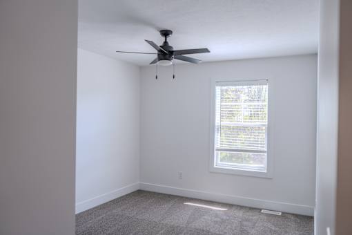 A room with a ceiling fan and a window.
