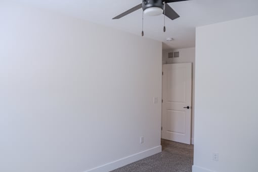 A room with a ceiling fan and a door.