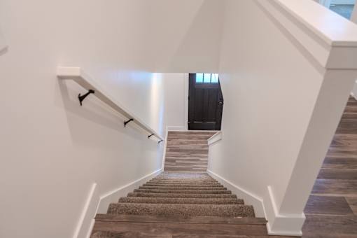 A staircase with a carpeted runner and white walls.