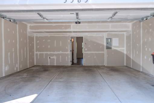 A garage with a door open and a wall with holes in it.