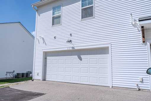A white garage door is closed and there is a window on the garage door.
