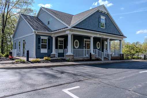 A small blue house with white columns and a porch.