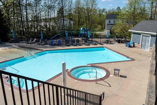 A large swimming pool with a slide and a hot tub.