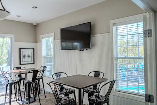 A room with a table and chairs and a television mounted on the wall.