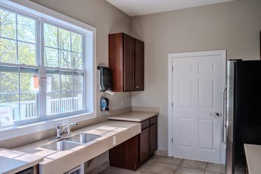 A kitchen with a sink, a window, and a refrigerator.