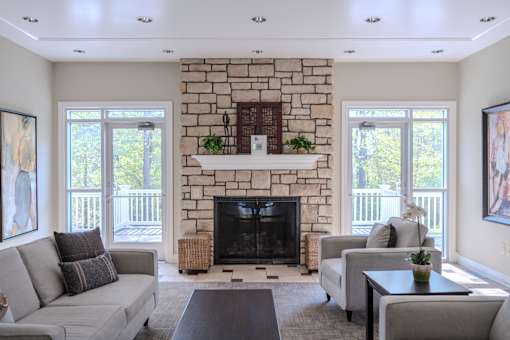 A living room with a stone fireplace and a grey couch.