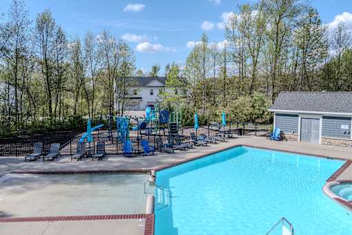 A large swimming pool with a diving board and a fence around it.