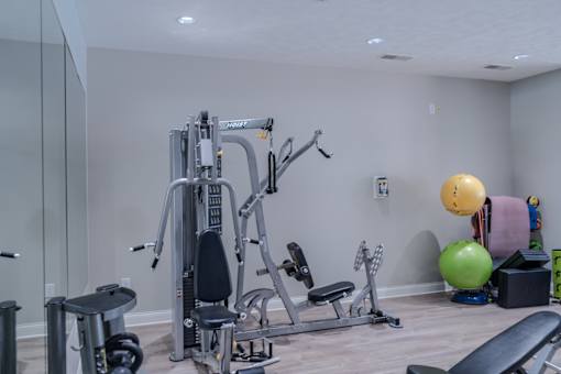 A home gym with a variety of equipment including a weight bench, dumbbells, and a medicine ball.