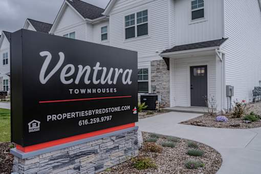 A sign for Ventura Townhouses with a website and phone number.