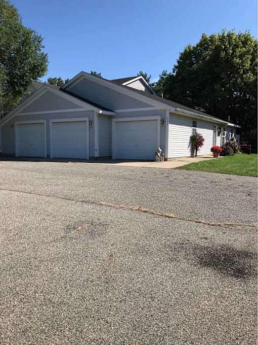 A two-car garage with a white house in the background.