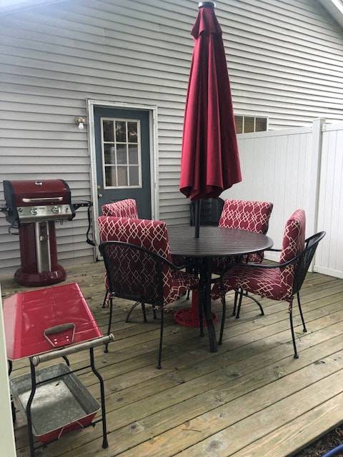 A red umbrella is above a table with chairs.