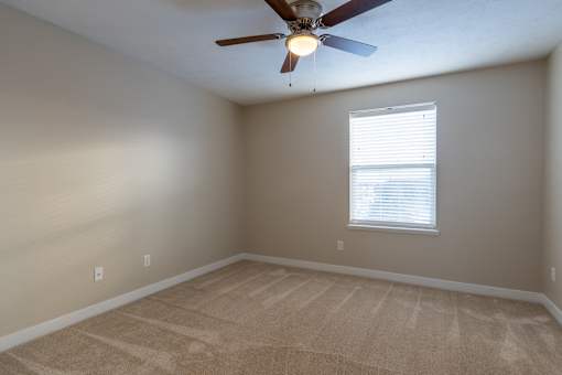A room with a ceiling fan and a window with blinds.