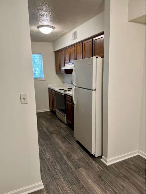 A kitchen with a white refrigerator and wooden cabinets.