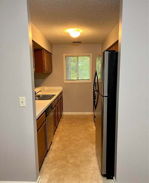 A kitchen with a black fridge and brown cabinets.