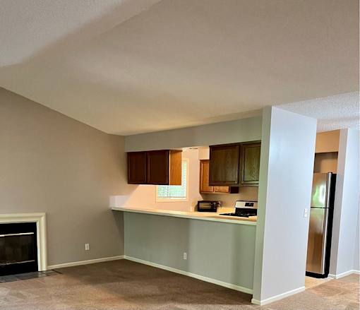 A kitchen with a fireplace and a refrigerator.
