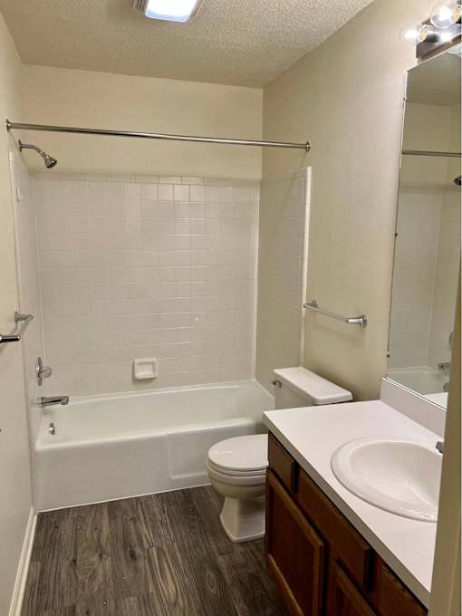 A white tiled bathroom with a toilet, sink, and bathtub.