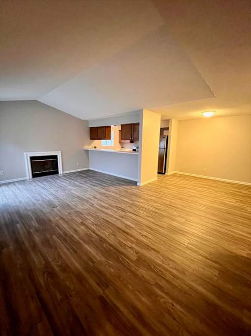 A room with wooden flooring and a fireplace.