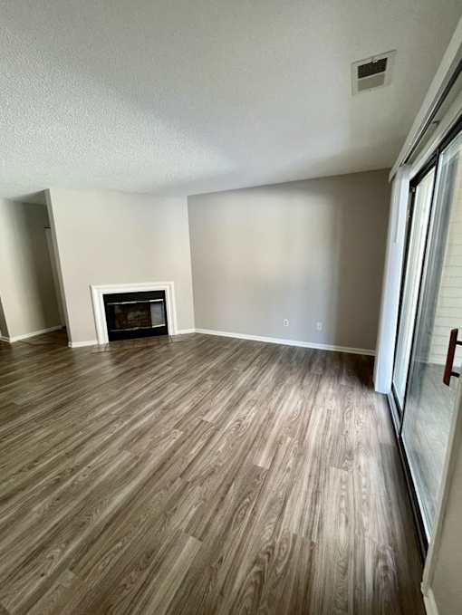 A room with a fireplace and wood flooring.