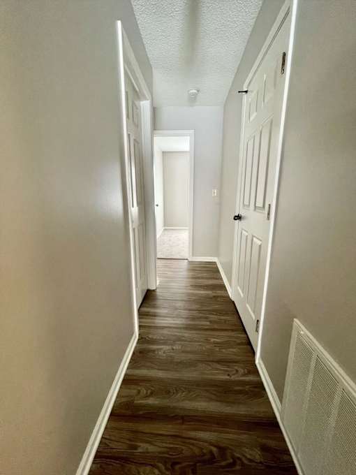 A long hallway with wood floors and white walls.
