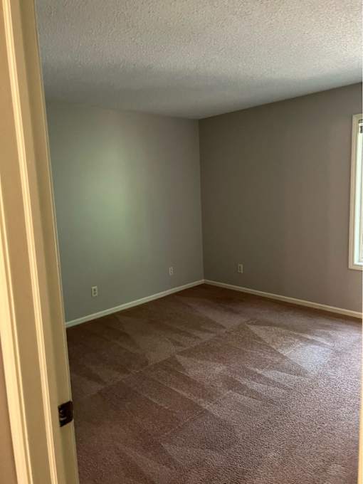 A room with a carpeted floor and a door on the left.