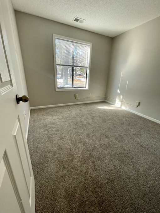 A room with a carpeted floor and a window.