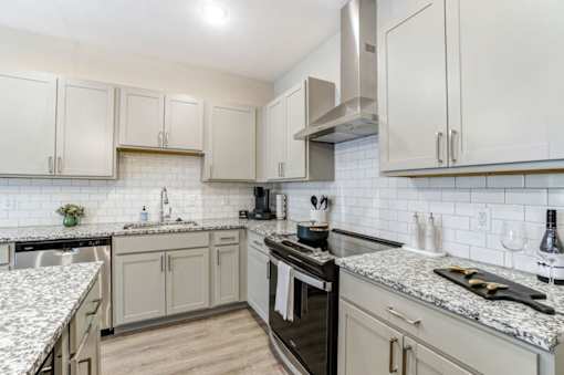 A kitchen with a black stove top oven and white cabinets at Eden Forest Townhomes Apartments, Kentwood , 49508