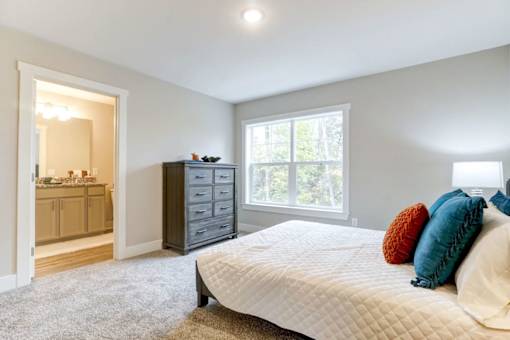 A bedroom with a large bed, a dresser, and a window at Eden Forest Townhomes Apartments, Kentwood , 49508