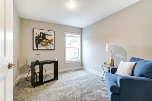 A living room with a blue couch and a painting on the wall at Eden Forest Townhomes Apartments, Kentwood , Michigan