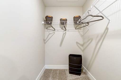 A white closet with a shelf and three hangers at Eden Forest Townhomes Apartments, Kentwood , MI, 49508
