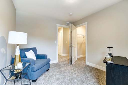 A blue couch sits in a room with a lamp and a table at Eden Forest Townhomes Apartments, Kentwood 