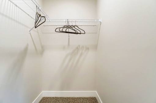 A white closet with a hanger and a carpet at Eden Forest Townhomes Apartments, Michigan