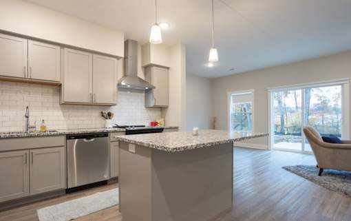 A modern kitchen with a large island and a stainless steel dishwasher at Eden Forest Townhomes Apartments, Michigan