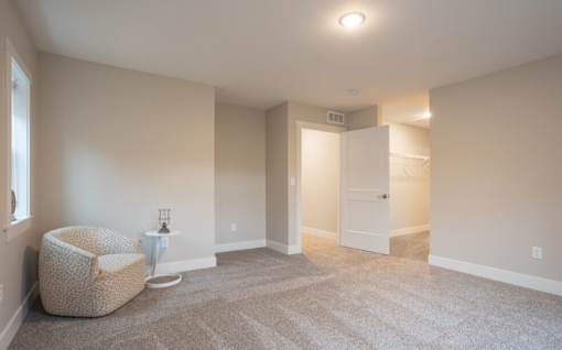 A spacious room with a chair and a small table at Eden Forest Townhomes Apartments, Kentwood , 49508