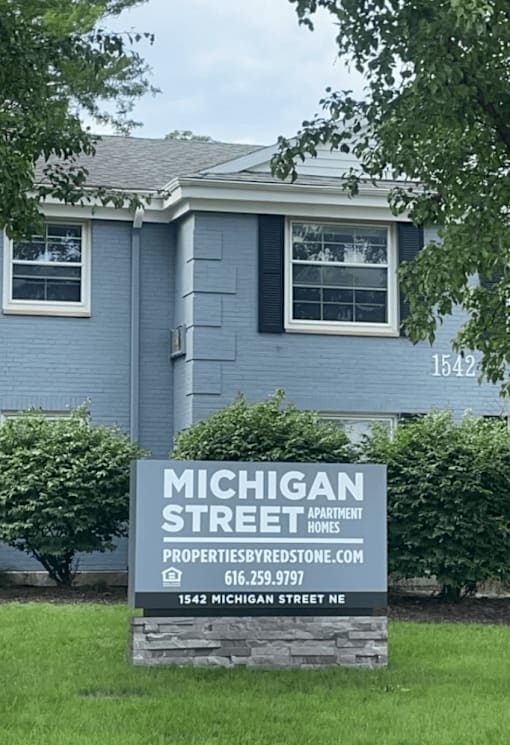 A blue house with a sign in front that says Michigan Street Apartment Homes at Michigan Street Apartment Homes, Michigan, 49503