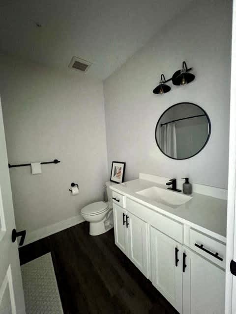 A bathroom with a toilet, sink, and mirror at Michigan Street Apartment Homes, Grand Rapids  