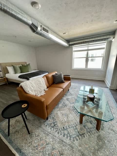A living room with a brown couch and a glass coffee table at Michigan Street Apartment Homes, Grand Rapids  , 49503