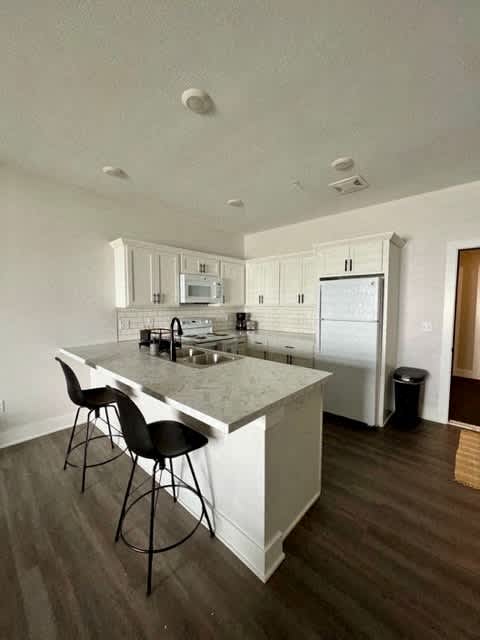 A kitchen with a white countertop and black barstools at Michigan Street Apartment Homes, Michigan