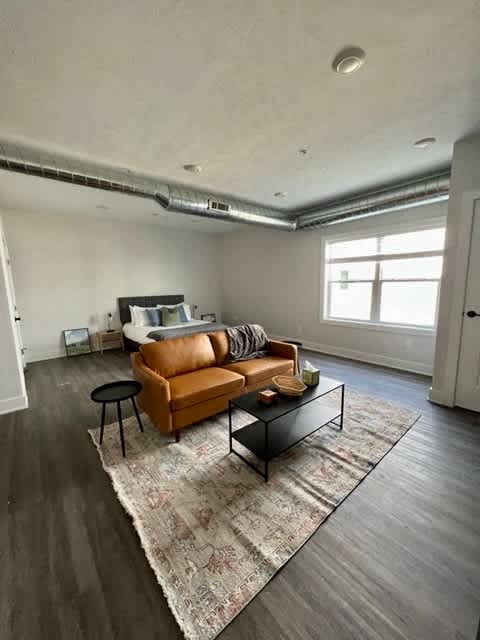 A living room with a brown leather couch, a black coffee table, and a patterned rug at Michigan Street Apartment Homes, Grand Rapids  