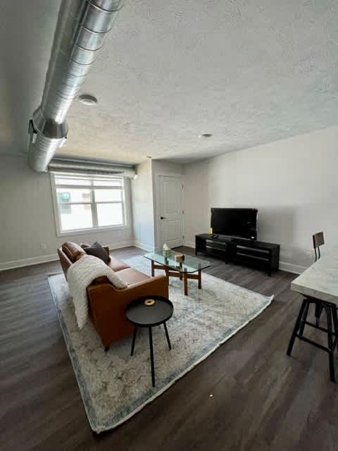 A living room with a brown couch and a white rug at Michigan Street Apartment Homes, Michigan, 49503