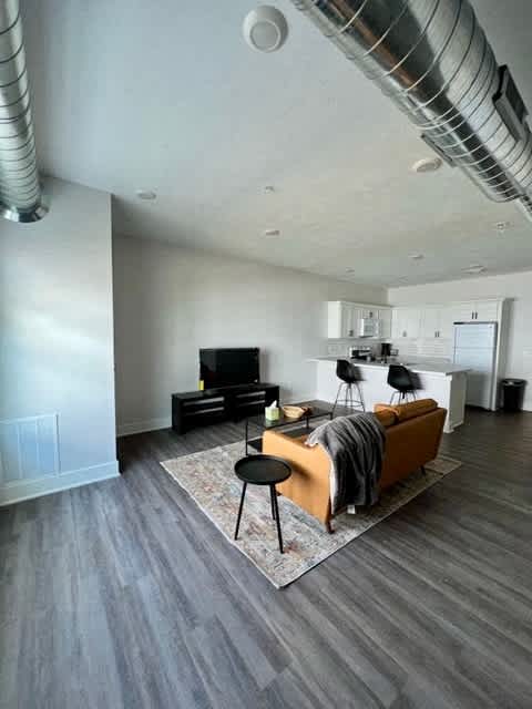 A living room with a grey floor and a white ceiling with a pipe at Michigan Street Apartment Homes, Grand Rapids  , Michigan
